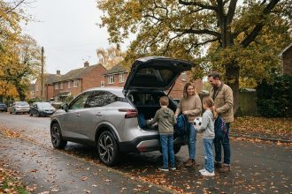 Famille chargeant ses affaires dans un Nissan Qashqai 2026 argent dans une rue résidentielle en automne