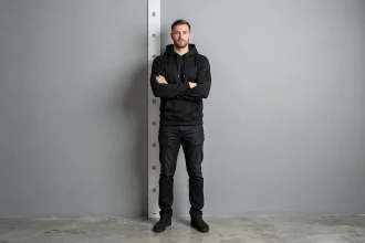 Homme mesurant sa taille contre un mètre ruban fixé au mur, illustrant le débat sur la vraie taille de Lacrim